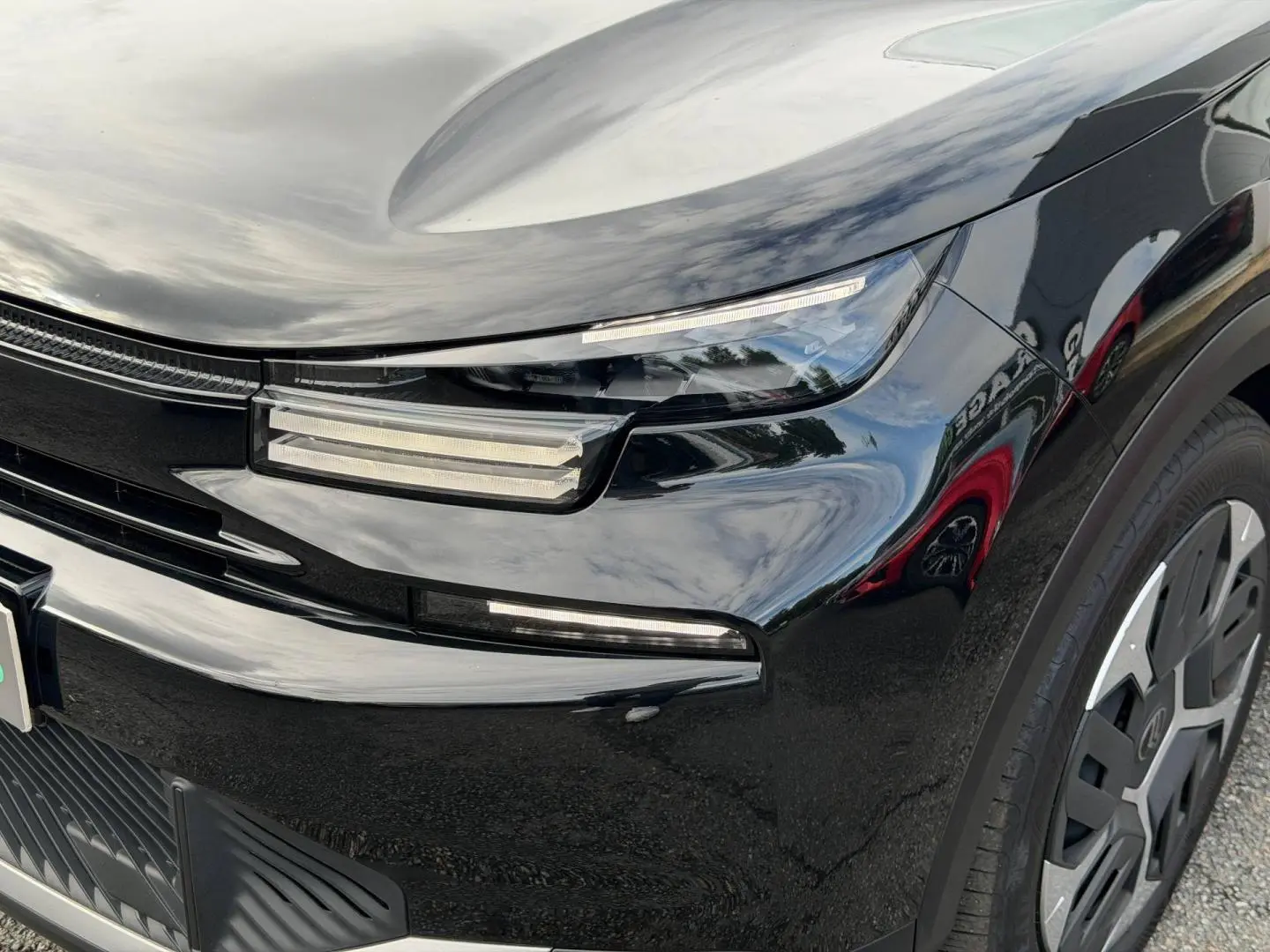 Gros plan sur l'avant droit noir Perla Nera d'une Citroën C4 2025, avec phares LED et jante alu visible.