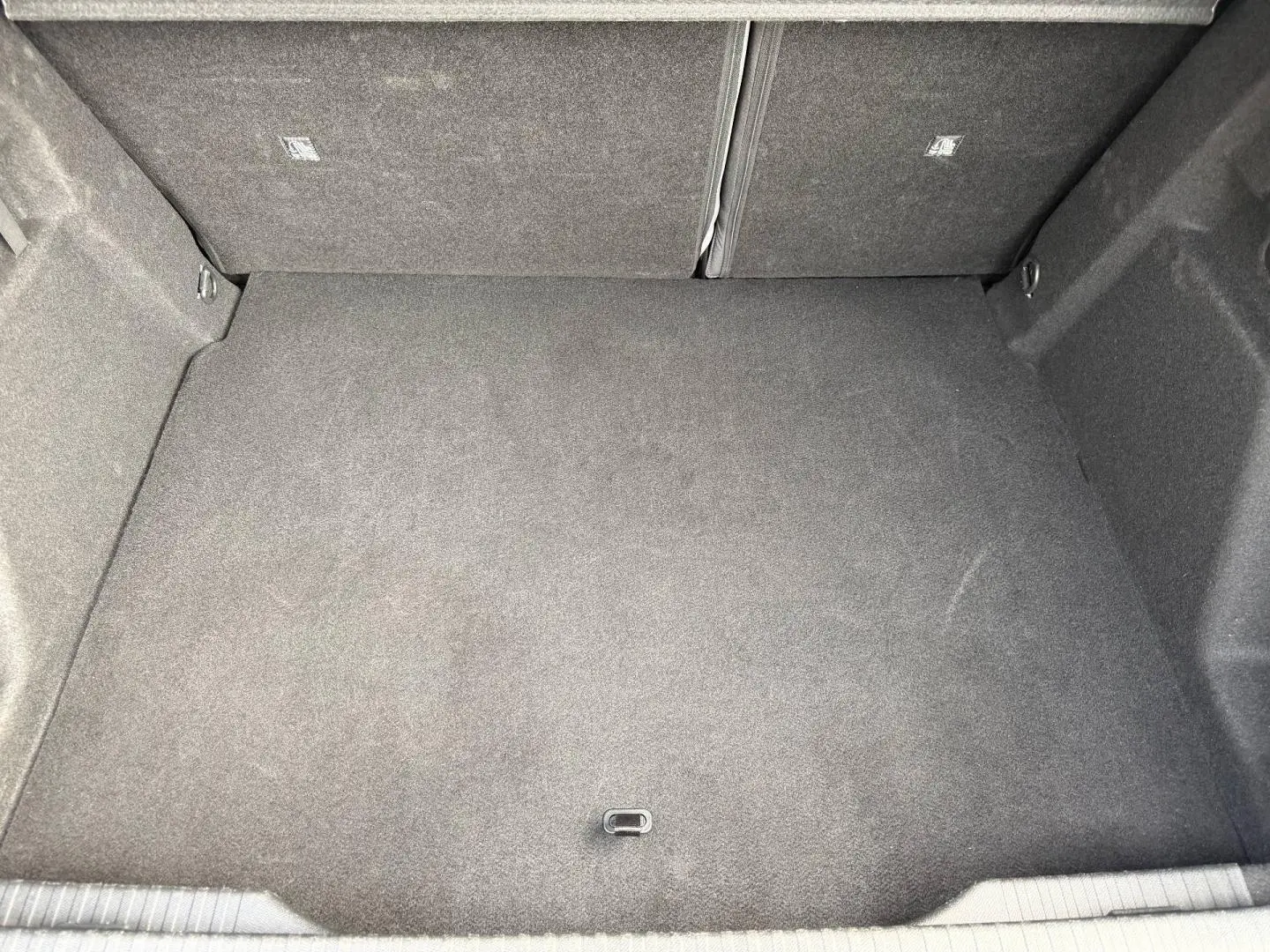 Coffre spacieux vu de dessus, revêtement gris foncé, banquette arrière rabattable visible en partie.