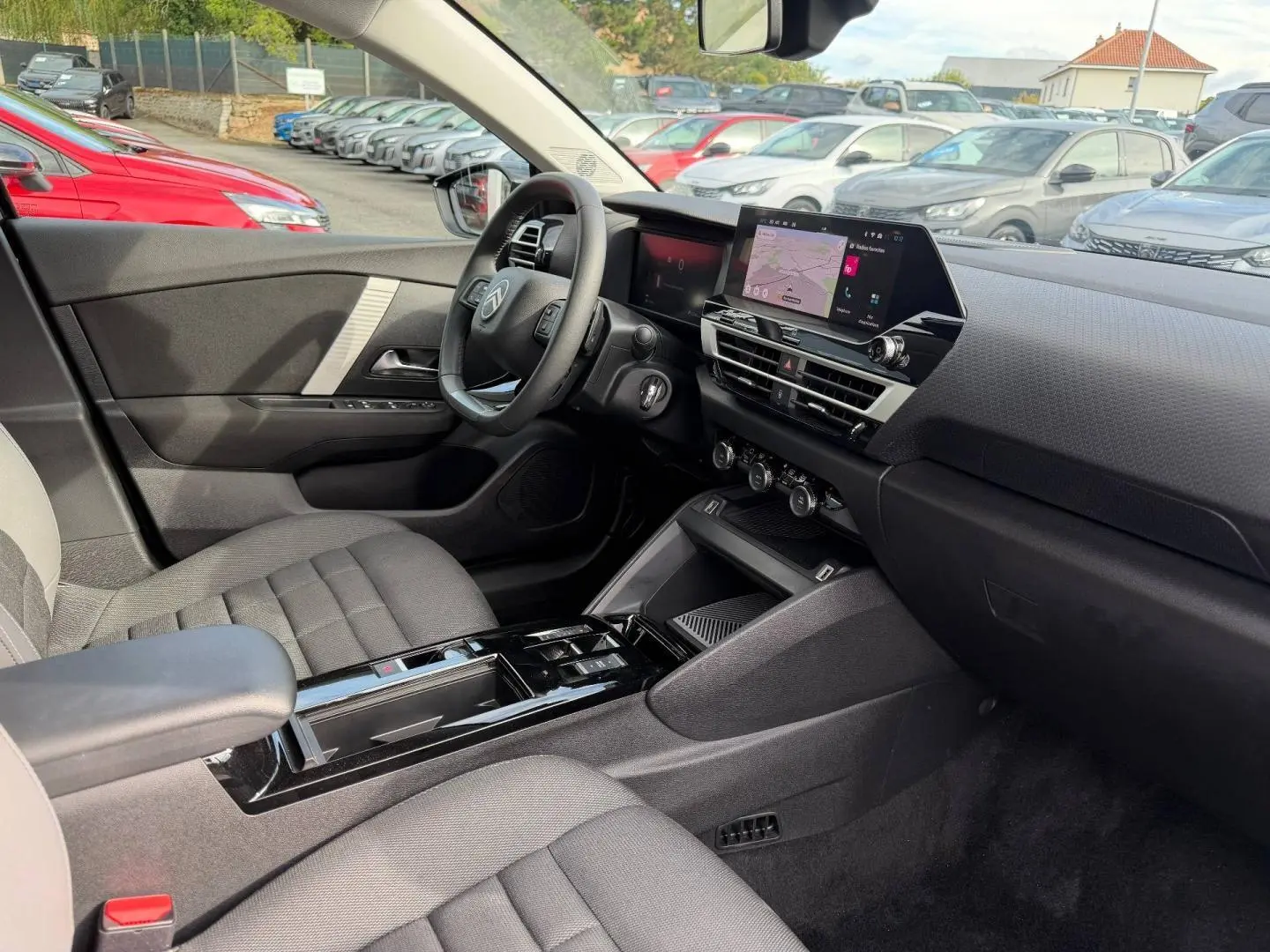 Vue intérieure côté conducteur de la Citroën C4 1.2 Hybride 2025 avec tableau de bord noir et écran tactile central.