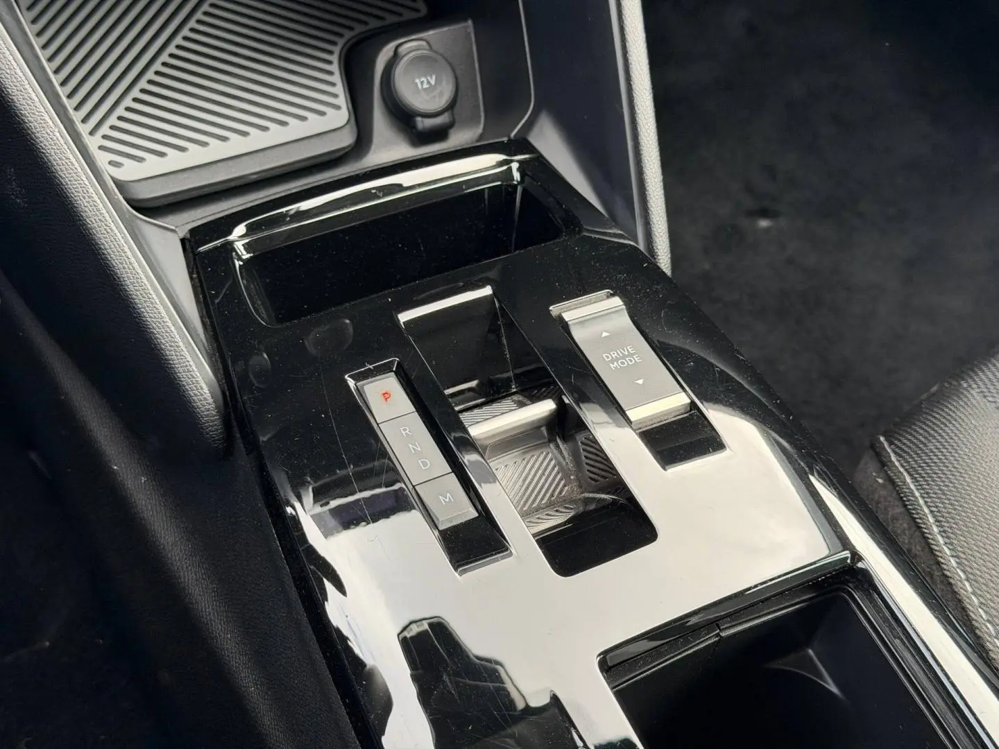 Gros plan sur la console centrale noire brillante avec levier de vitesses automatique et bouton Drive Mode du Citroën C4 hybride.