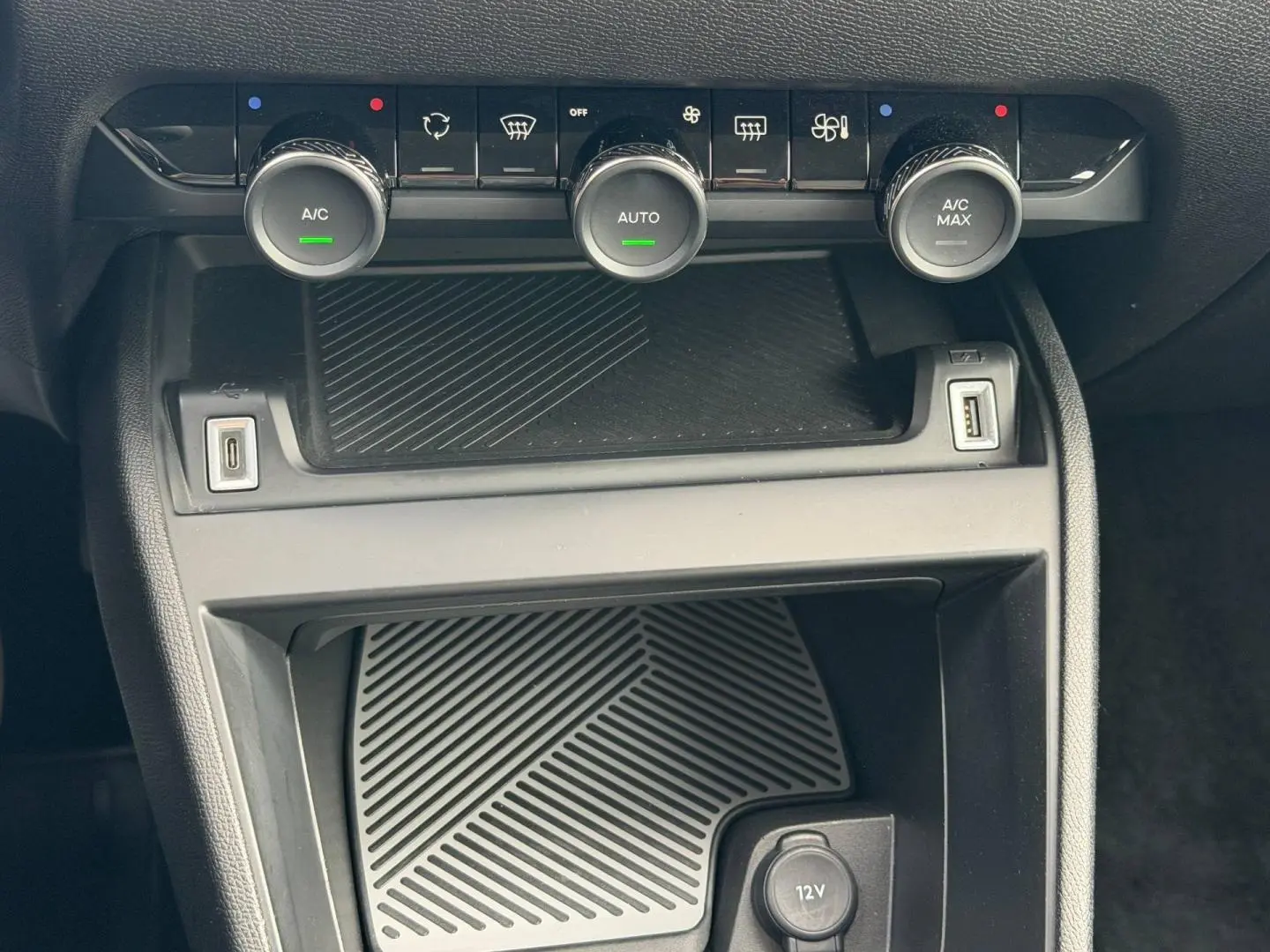 Vue rapprochée de la console centrale de la Citroën C4 1.2 Hybride 145ch, avec commandes climatisation et ports USB.
