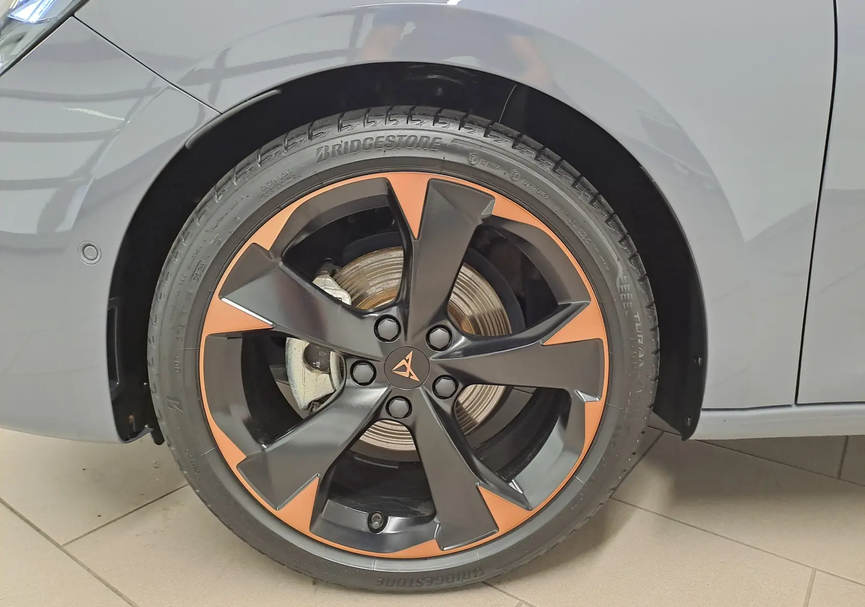 Gros plan sur la jante cuivrée 18'' Performance du côté avant droit d'une CUPRA Leon gris Graphène.