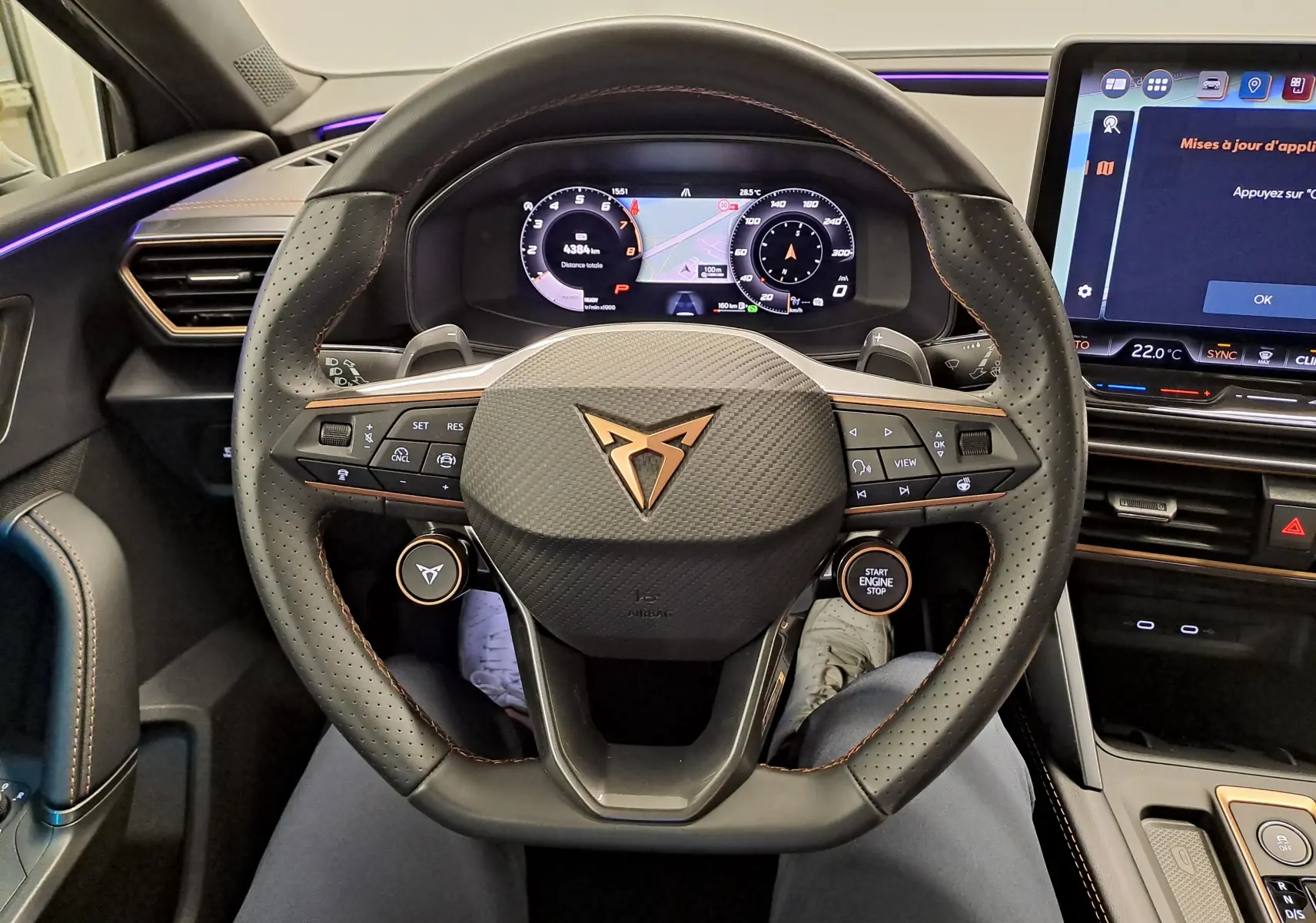 Vue centrée sur le volant cuir perforé de la CUPRA Leon 2025 avec logo cuivré et tableau de bord numérique.