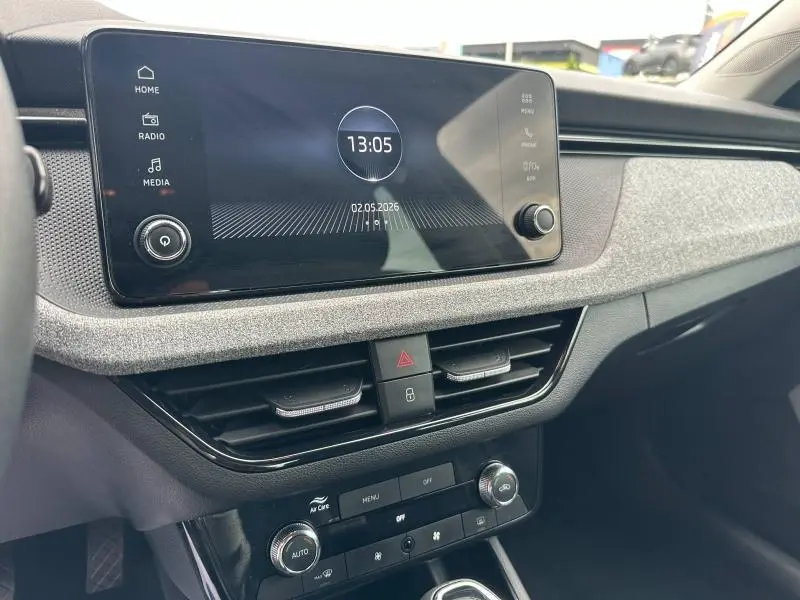 Tableau de bord de la Skoda Scala 2025 avec écran tactile central et garniture tissu gris clair.