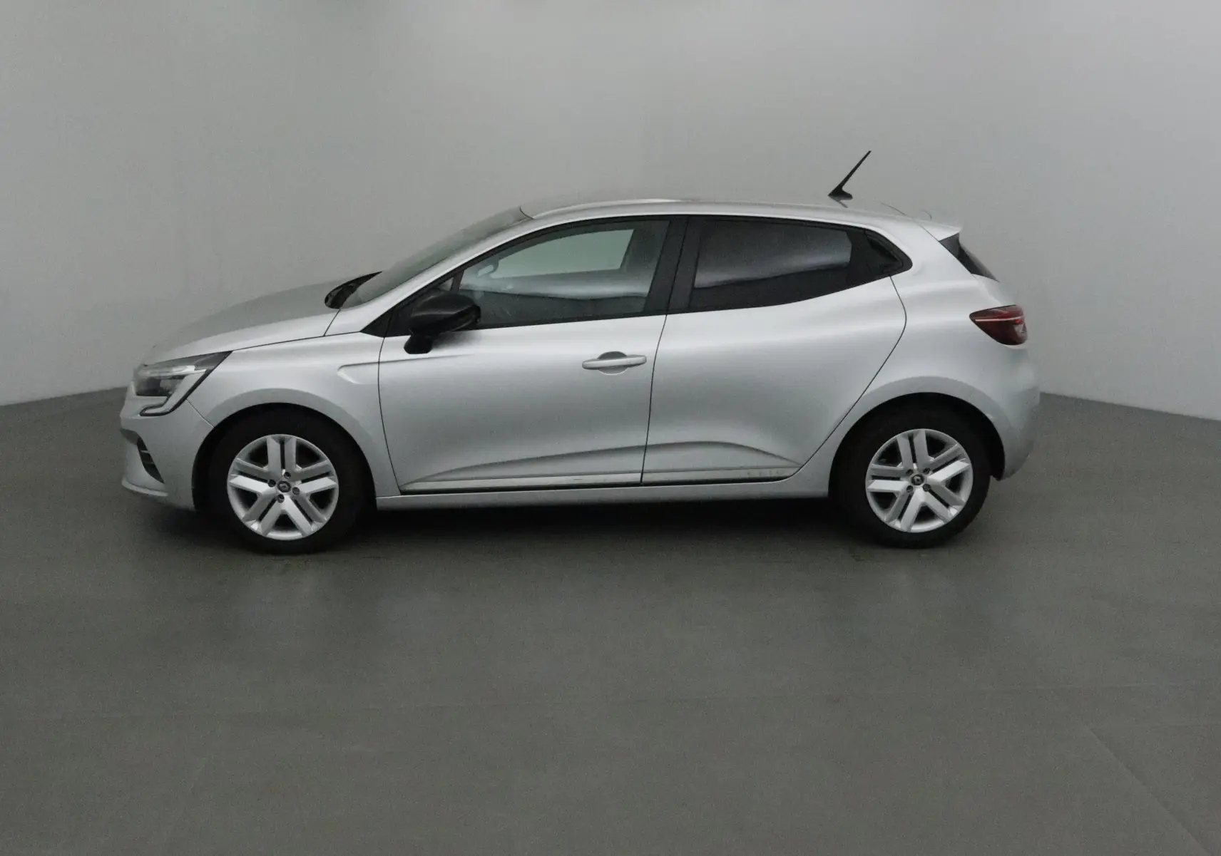 Profil côté gauche d'une Renault Clio V gris platine 2021 avec jantes alliage et rétroviseurs noirs.