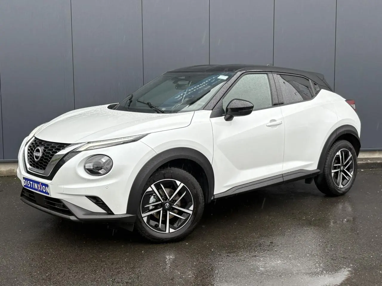 Nissan Juke blanc nacré en 3/4 avant droit, toit noir contrasté et jantes alliage 17 pouces.