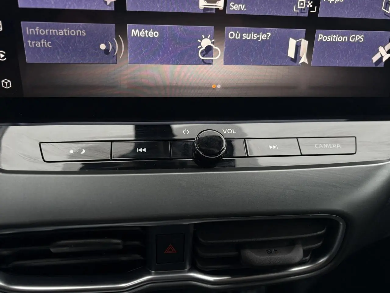 Gros plan sur la console centrale du Nissan Juke blanc nacré 2025, mettant en valeur les commandes multimédia et la ventilation.