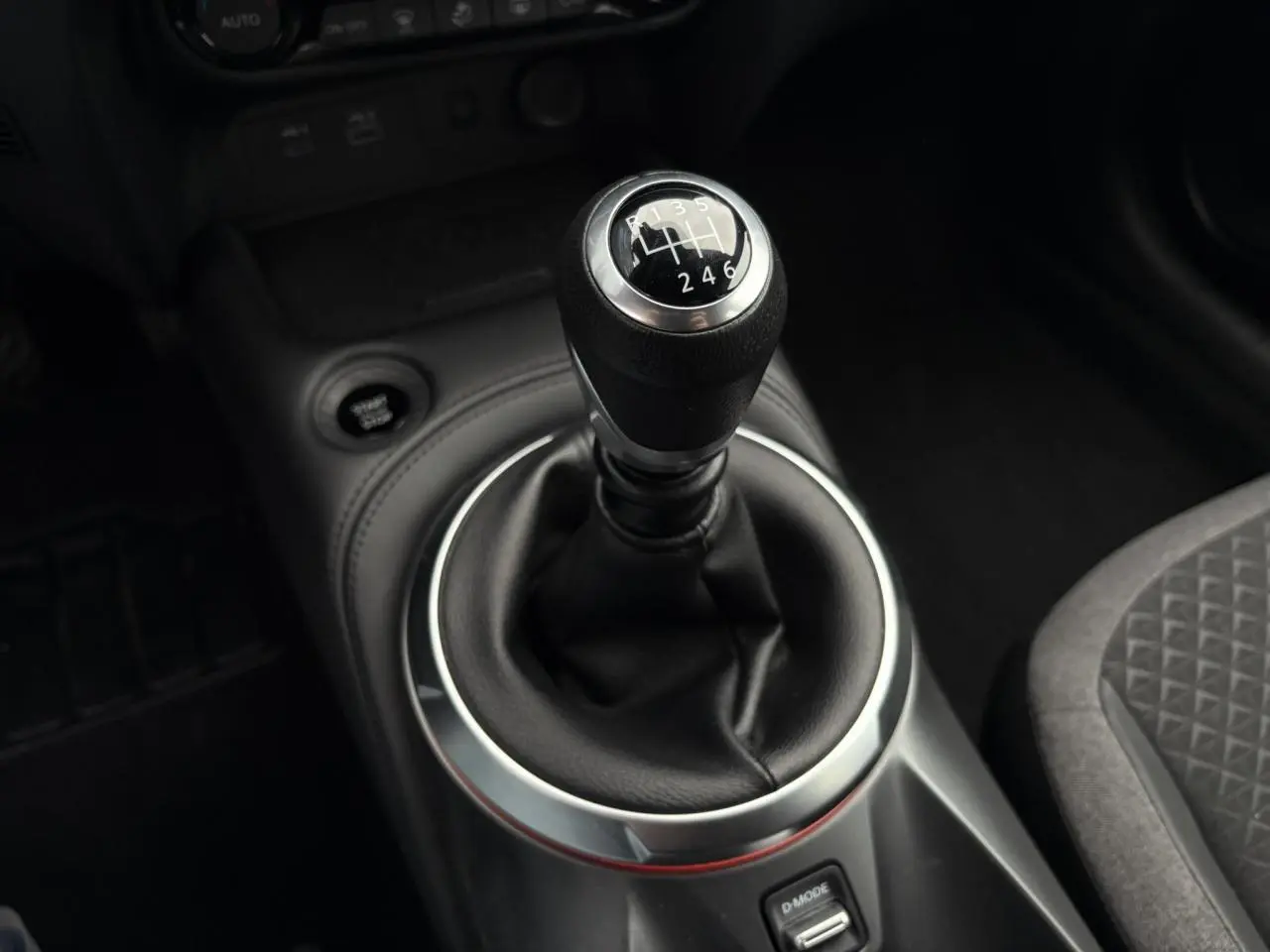 Gros plan sur le levier de vitesses manuel entouré de cuir noir dans l'habitacle du Nissan Juke 2025.