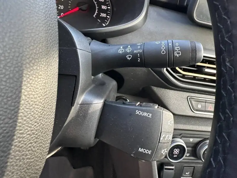 Gros plan sur la commande de phares et radio du tableau de bord d'une Dacia Sandero 2025 couleur Kaki Lichen.