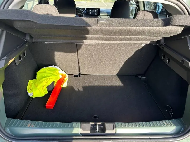 Coffre ouvert vu de l'arrière d'une Dacia Sandero 2025 kaki lichen avec gilet jaune et triangle de signalisation.