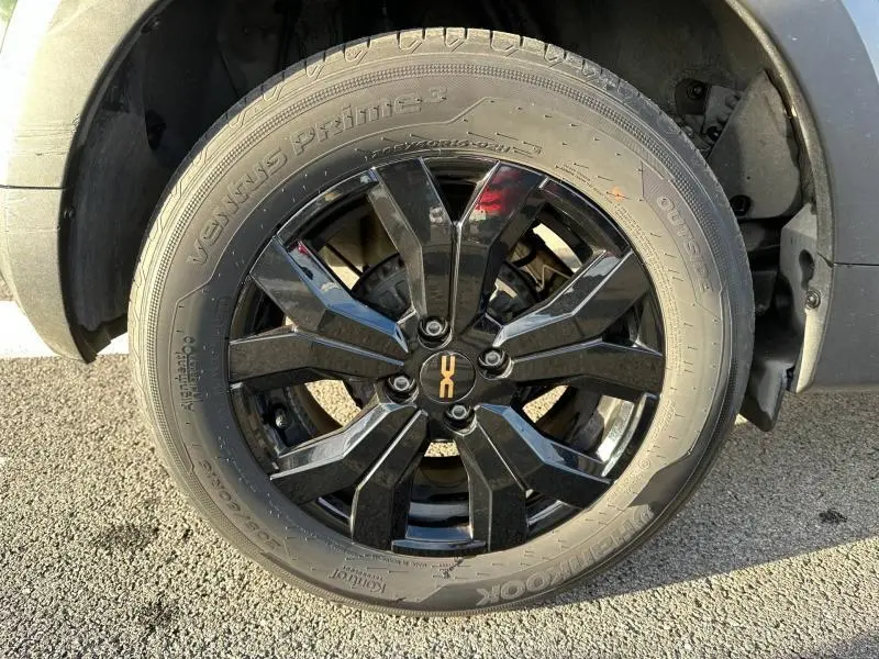 Gros plan sur la roue avant gauche du Dacia Sandero Stepway Extreme 2025 en Kaki Lichen avec jante noire brillante à motif géométrique.