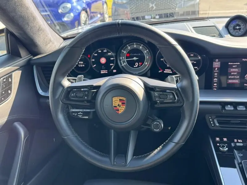 Vue centrée sur le volant cuir noir de la Porsche 911 Turbo S 2020, avec tableau de bord numérique et écran tactile visible.