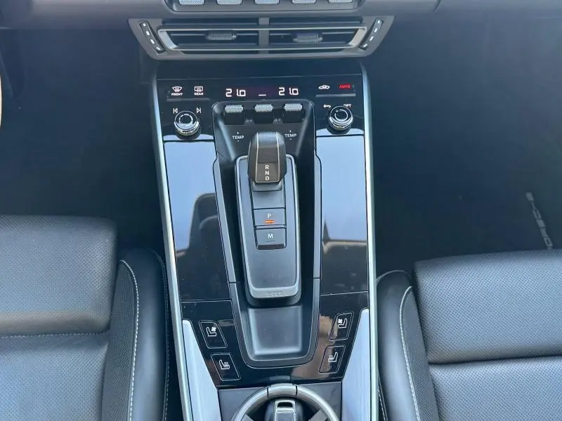 Vue plongeante sur la console centrale noire brillante de la Porsche 911 Turbo S 2020 avec levier de vitesse PDK et sièges en cuir noir.