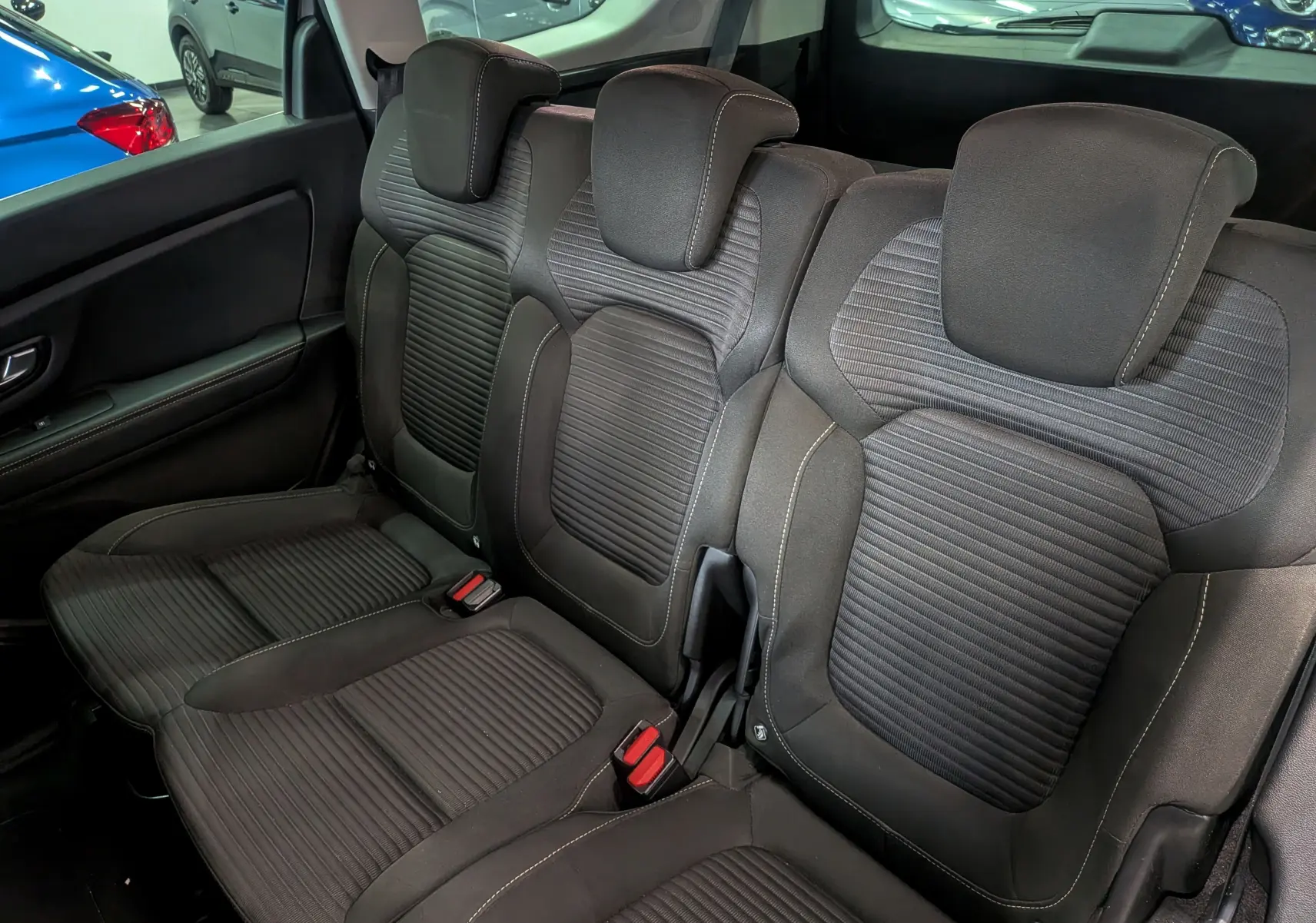 Vue intérieure sur la banquette arrière en tissu noir du Renault Grand Scenic IV, avec appuie-têtes et ceintures visibles.