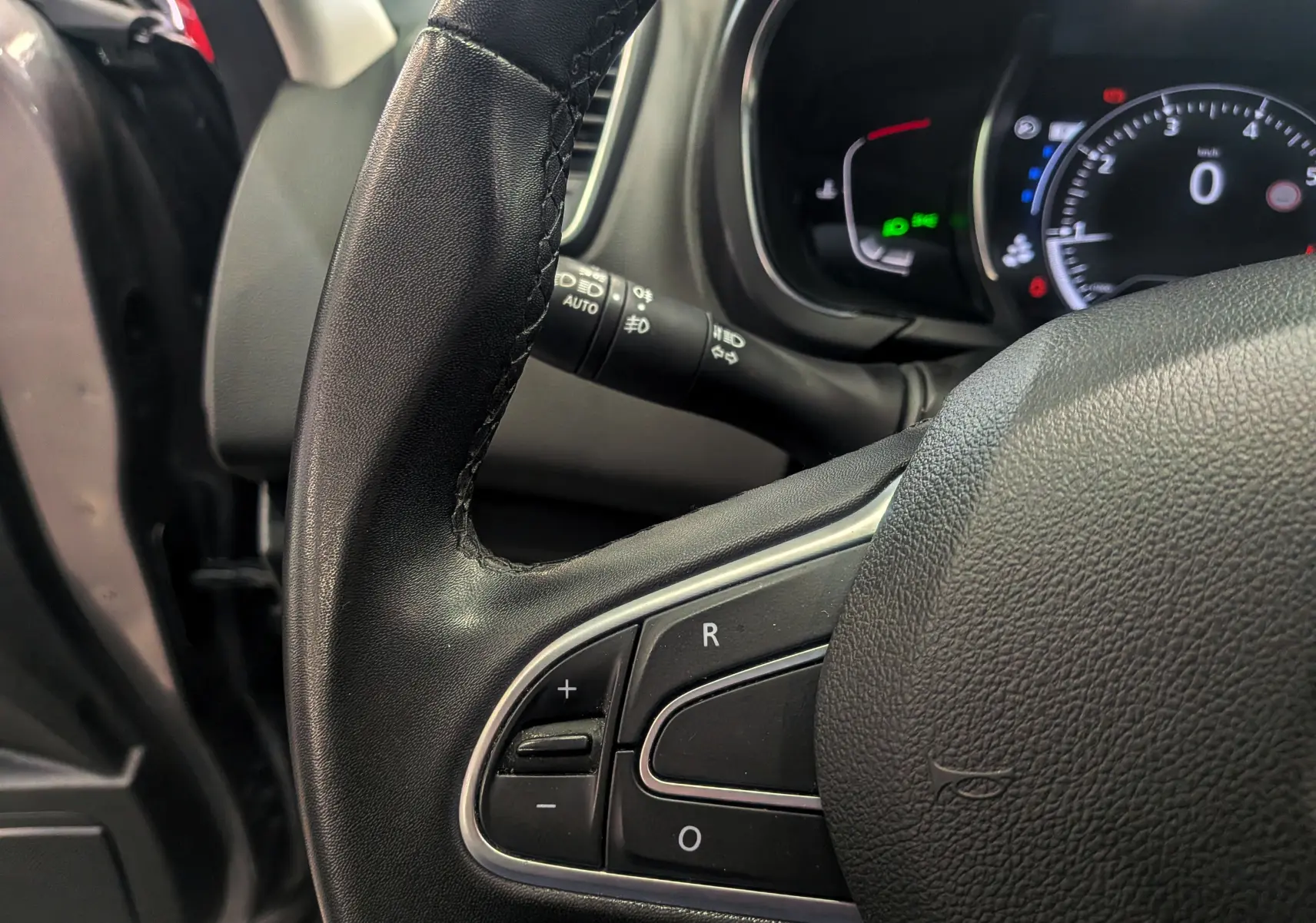Gros plan sur le volant noir du Renault Grand Scenic IV 2023, montrant les commandes de régulateur de vitesse.