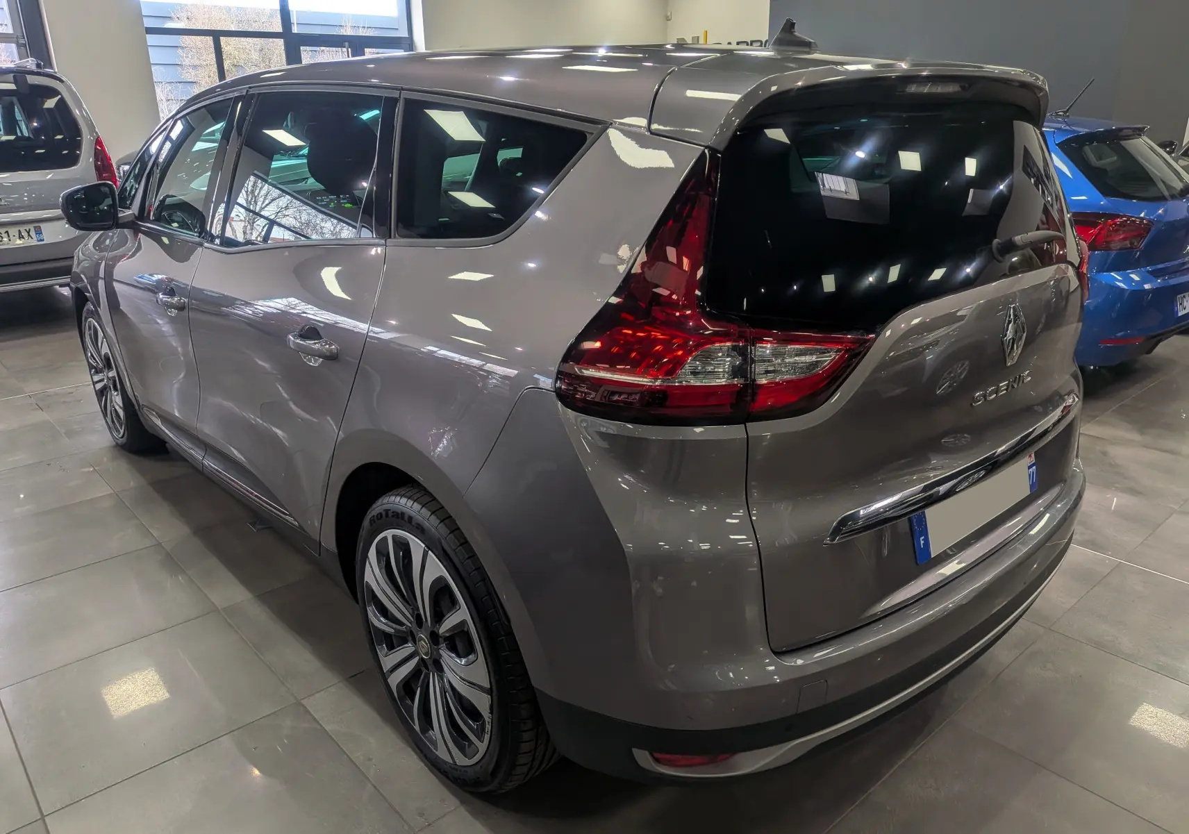 Vue 3/4 arrière droite du Renault Grand Scénic IV gris Cassiopé, mettant en valeur ses feux arrière et jantes stylisées.