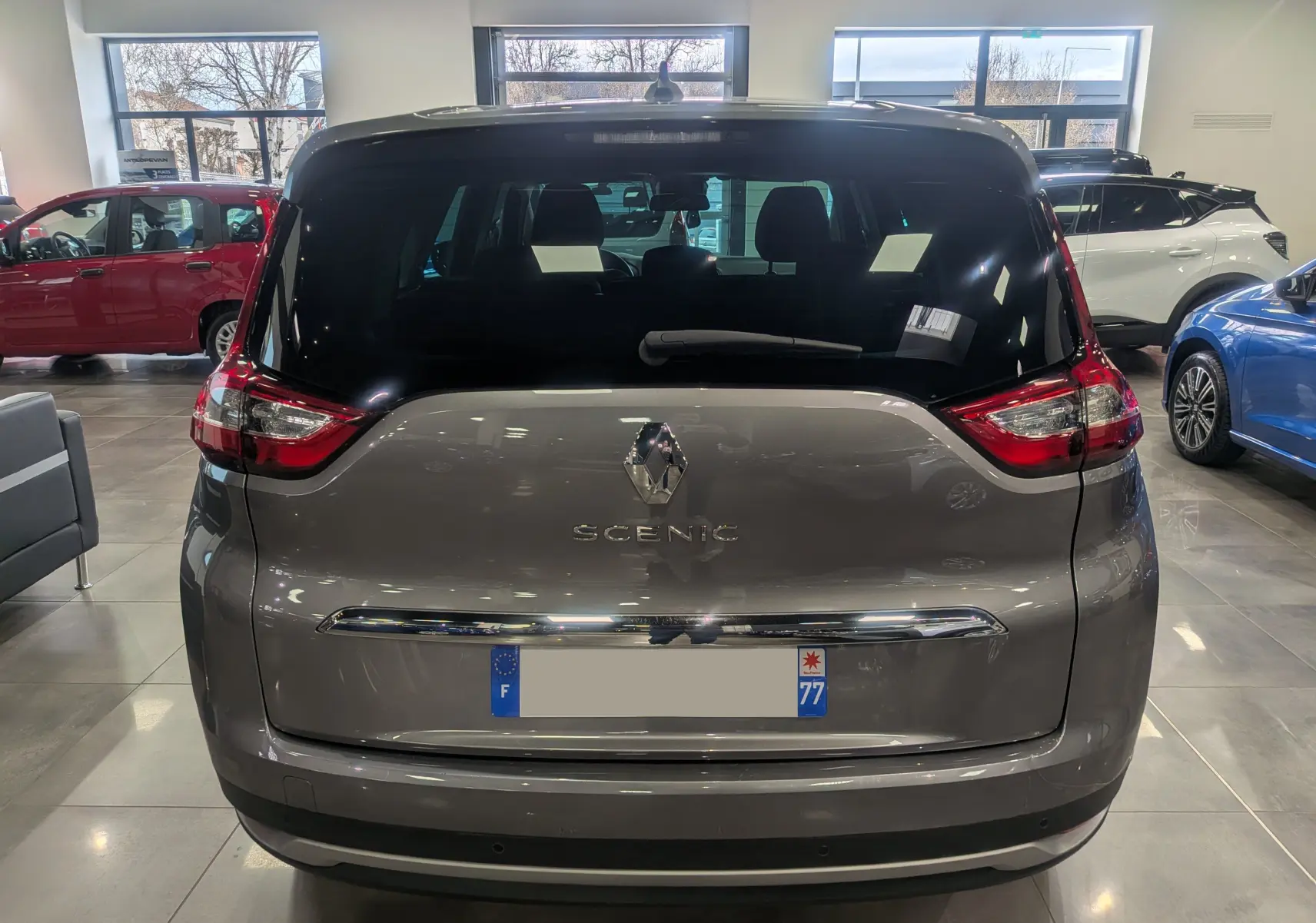 Vue arrière du Renault Grand Scénic IV gris Cassiopé 2023 en intérieur, avec logo et feux distinctifs visibles.