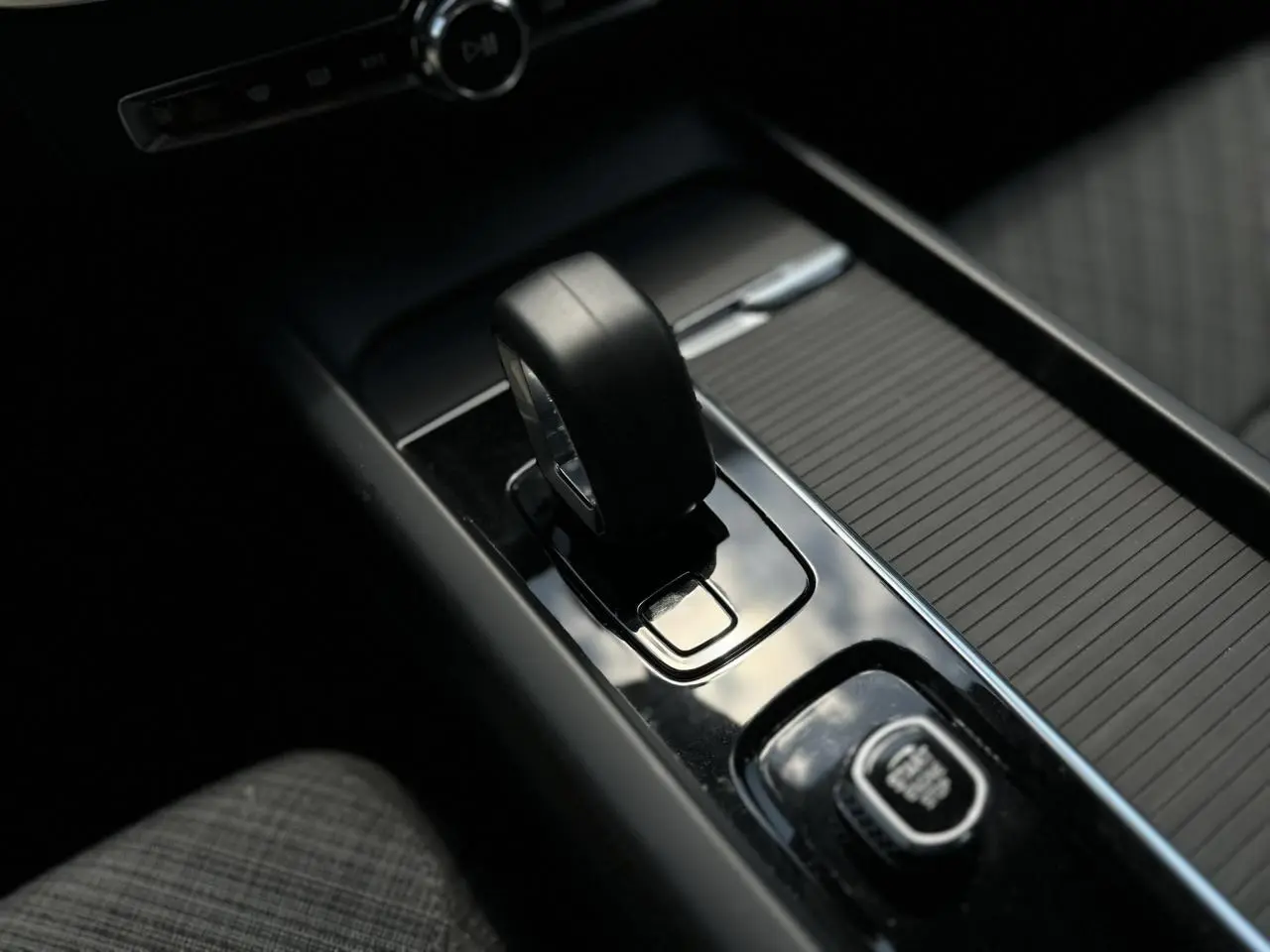 Gros plan sur le levier de vitesses noir et la commande Start/Stop dans la console centrale d'une Volvo S60 rouge Fusion 2024.