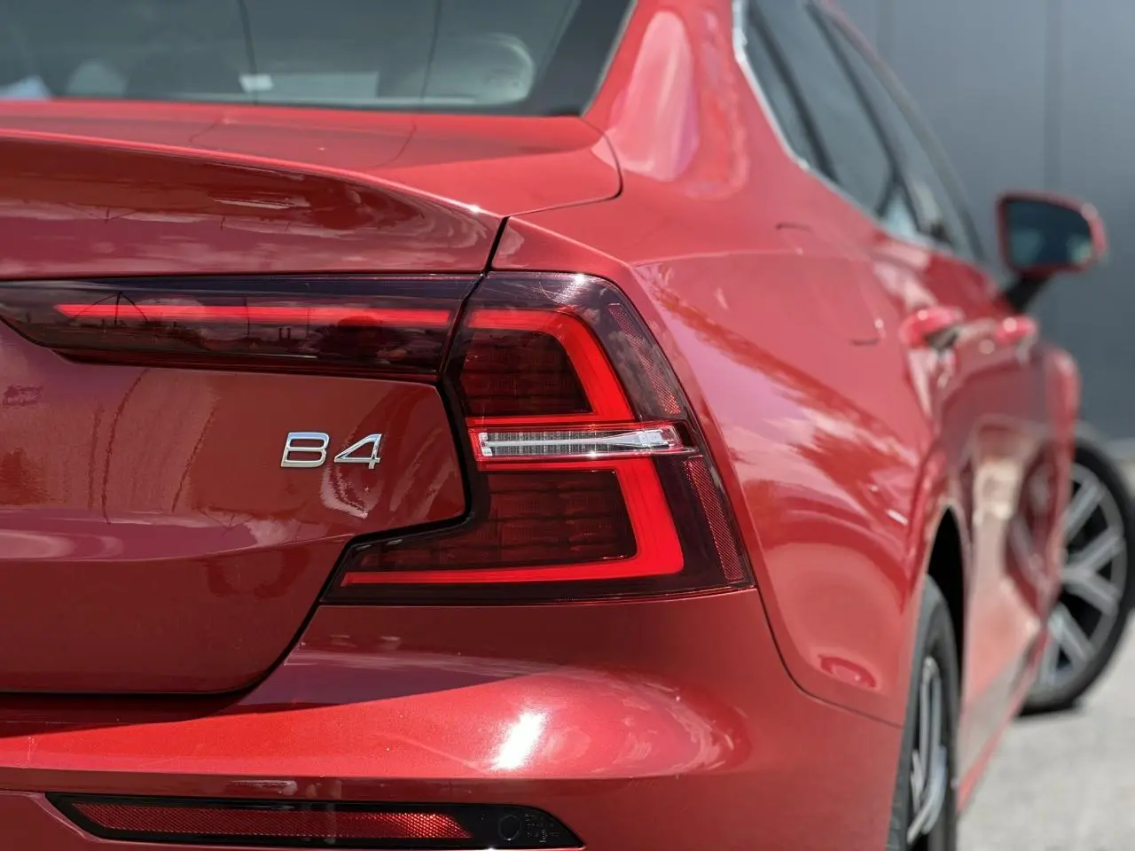 Gros plan sur l'arrière droit rouge Fusion du Volvo S60 B4 2024, avec feu arrière LED et logo B4 visible.
