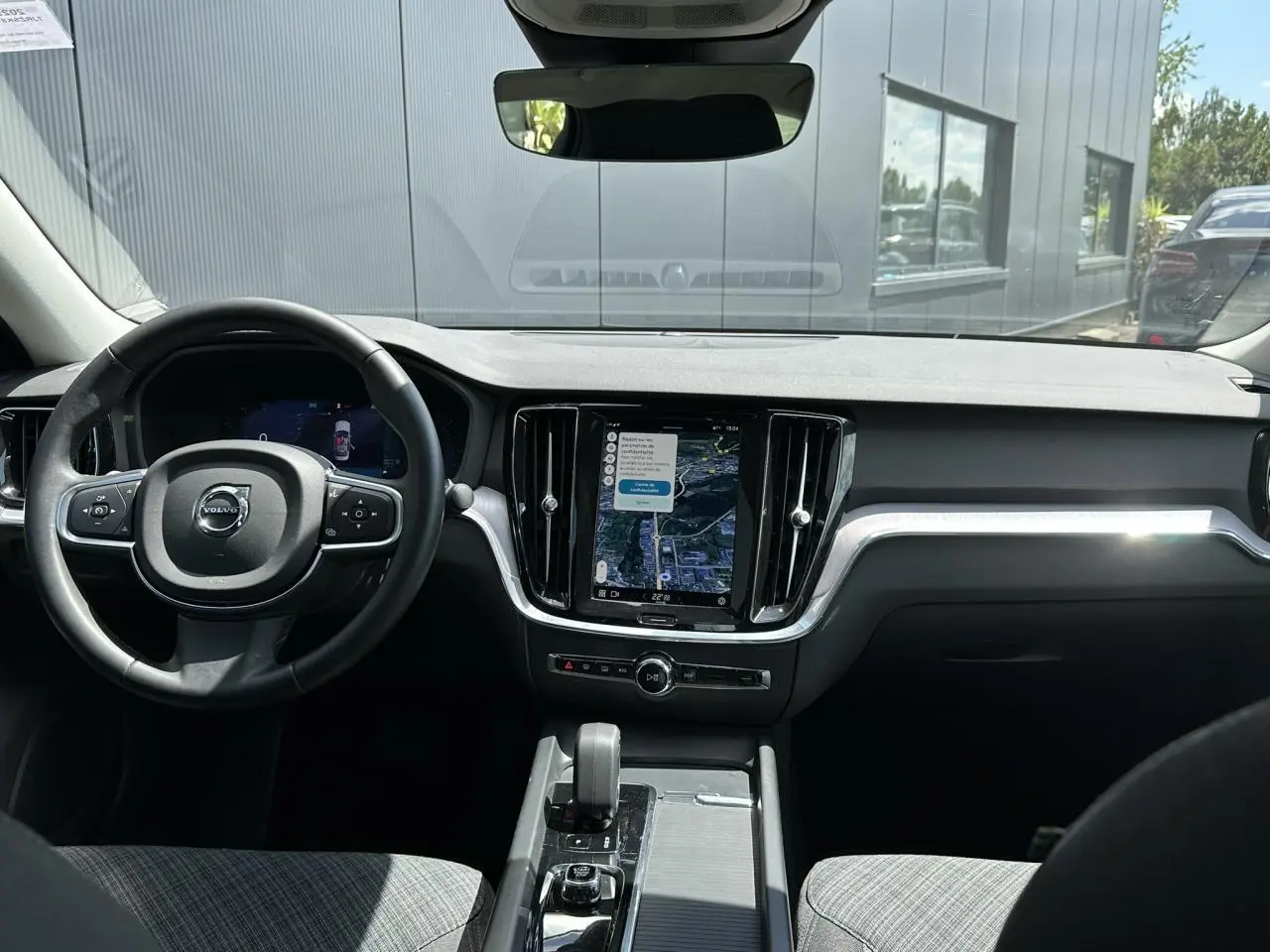 Vue intérieure avant du tableau de bord de la Volvo S60 rouge Fusion 2024 avec écran tactile GPS et volant multifonction.