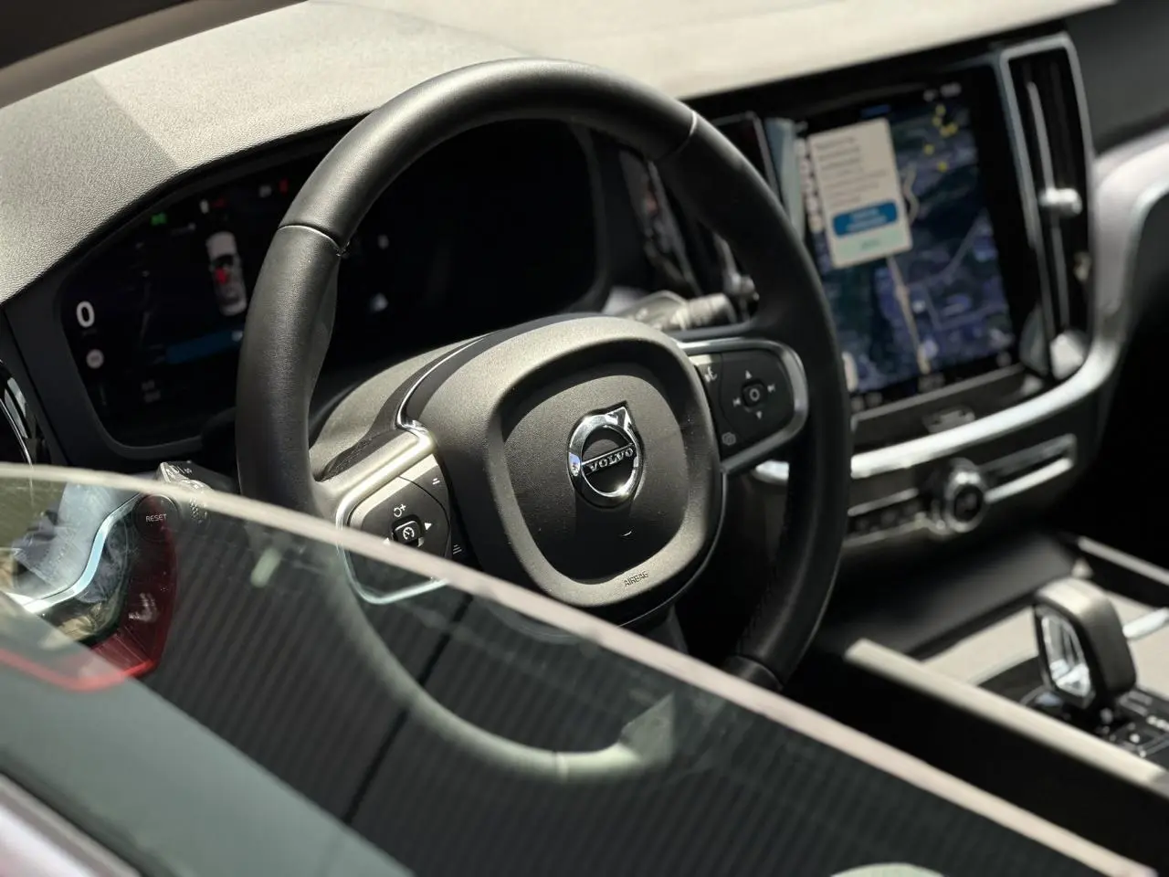 Vue rapprochée du volant et du tableau de bord numérique d'une Volvo S60 2024 avec écran tactile vertical.