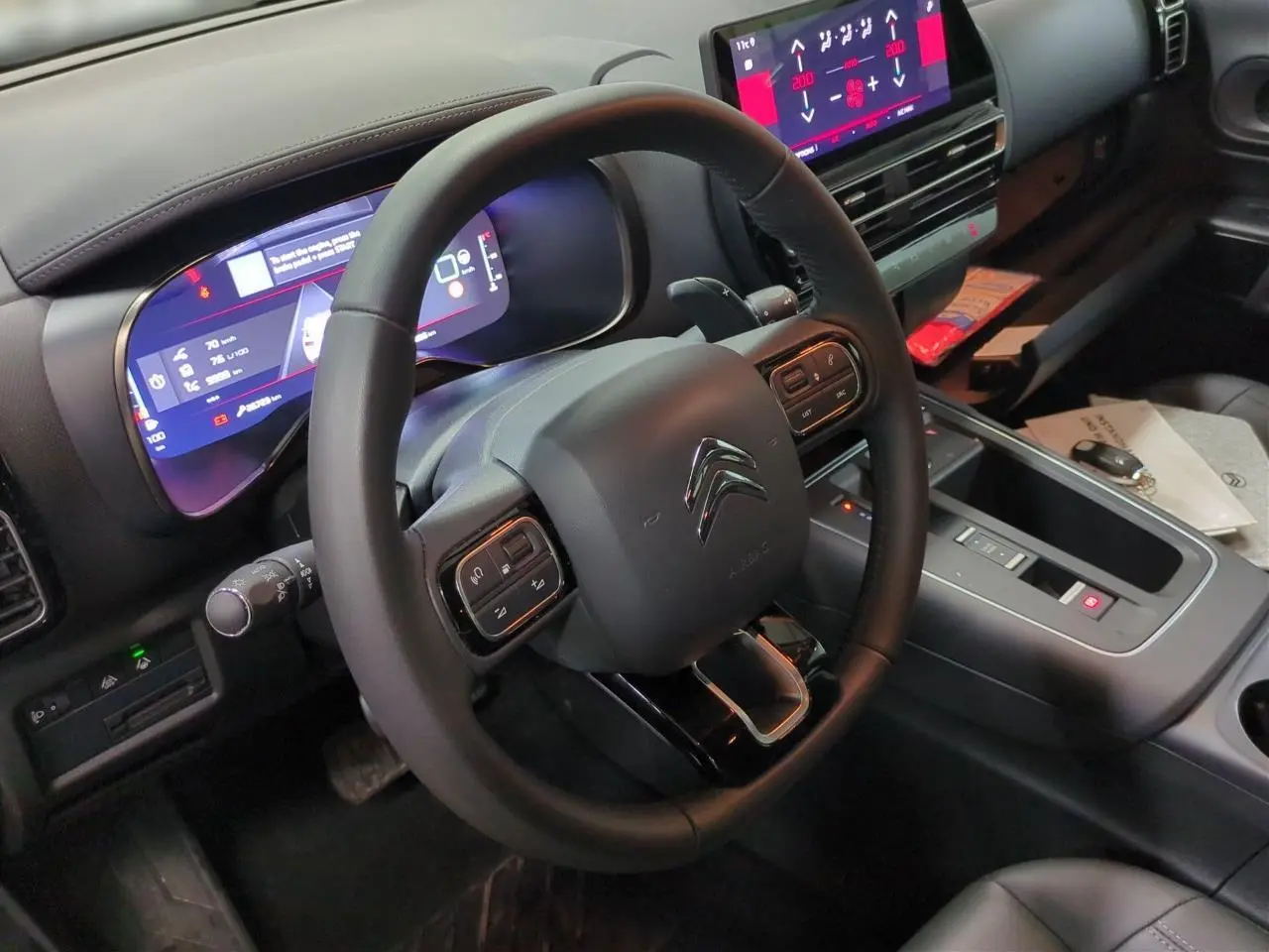 Vue intérieure centrée sur le volant cuir noir et le tableau de bord numérique du Citroën C5 Aircross Hybrid gris Platinium.