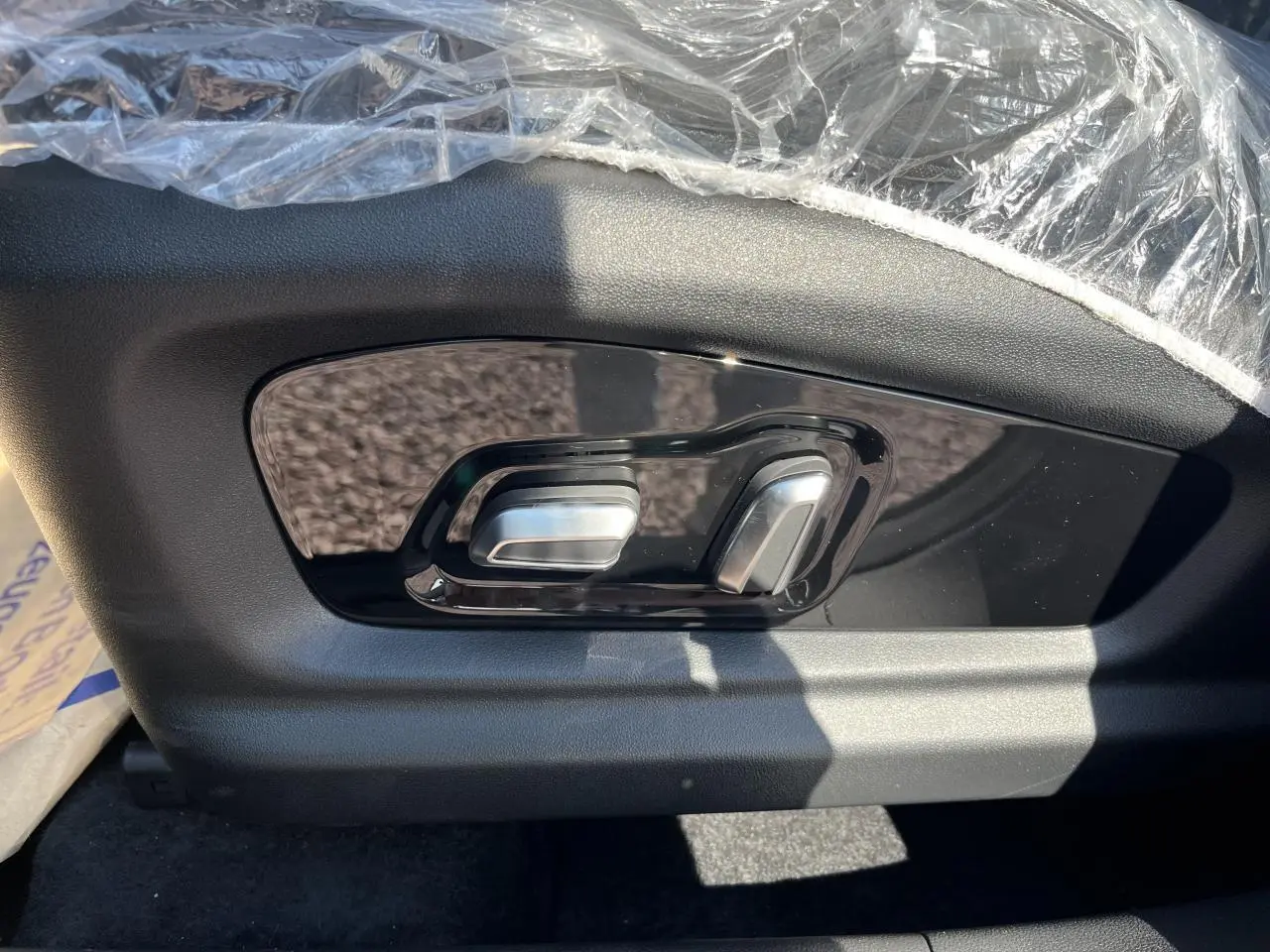 Gros plan sur les commandes de réglage électrique du siège côté conducteur du JAECOO J7 gris olive.