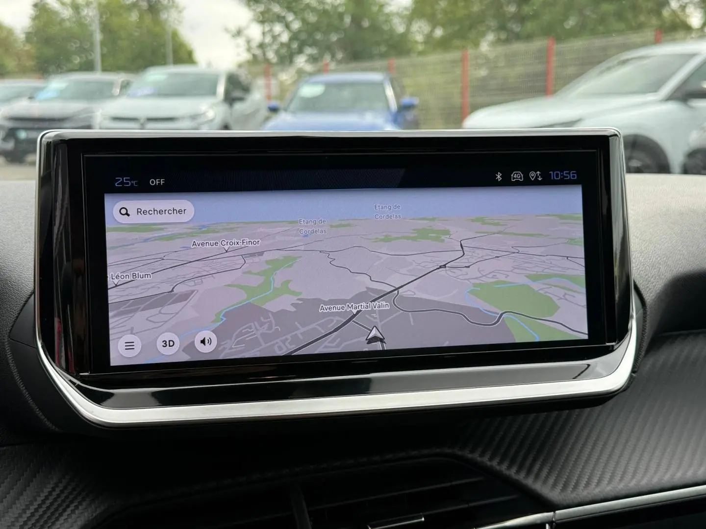 Vue intérieure centrée sur l'écran tactile du système de navigation de la Peugeot 208 2025, avec reflet extérieur flou.