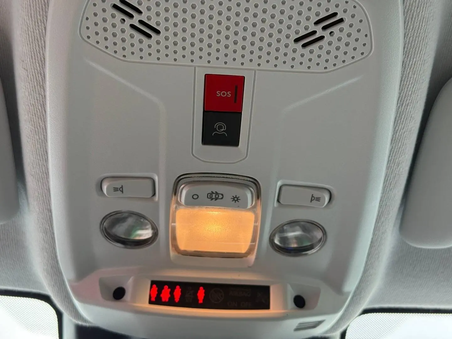 Vue en gros plan du plafonnier intérieur gris avec bouton SOS rouge et éclairage allumé dans une Peugeot 208 2025.