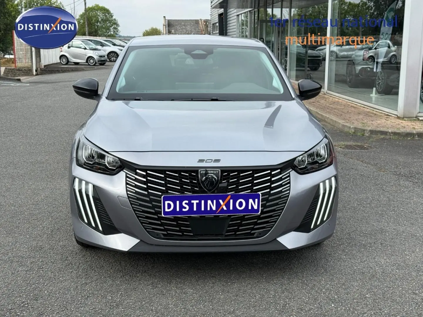 Peugeot 208 gris Artense vue de face, mettant en valeur la calandre noire et les feux LED distinctifs en griffes.