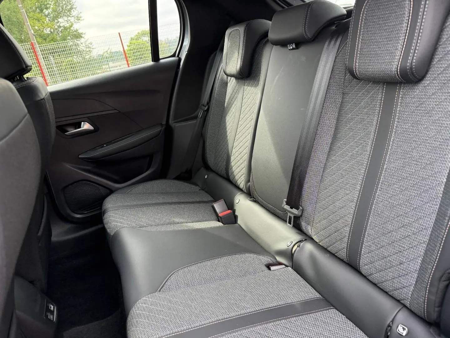 Vue intérieure sur la banquette arrière en tissu gris et cuir noir de la Peugeot 208 1.2 100ch Allure 2025.