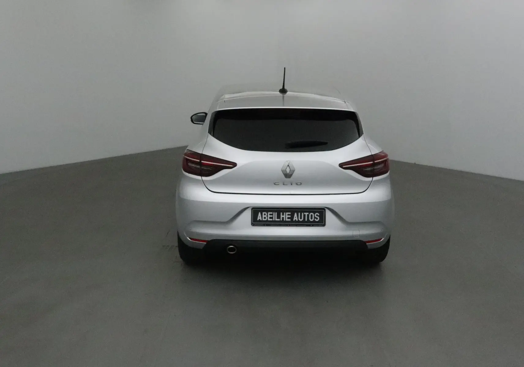 Vue arrière d'une Renault Clio V gris platine 2021 avec feux arrière LED et plaque Abeilhe Autos.