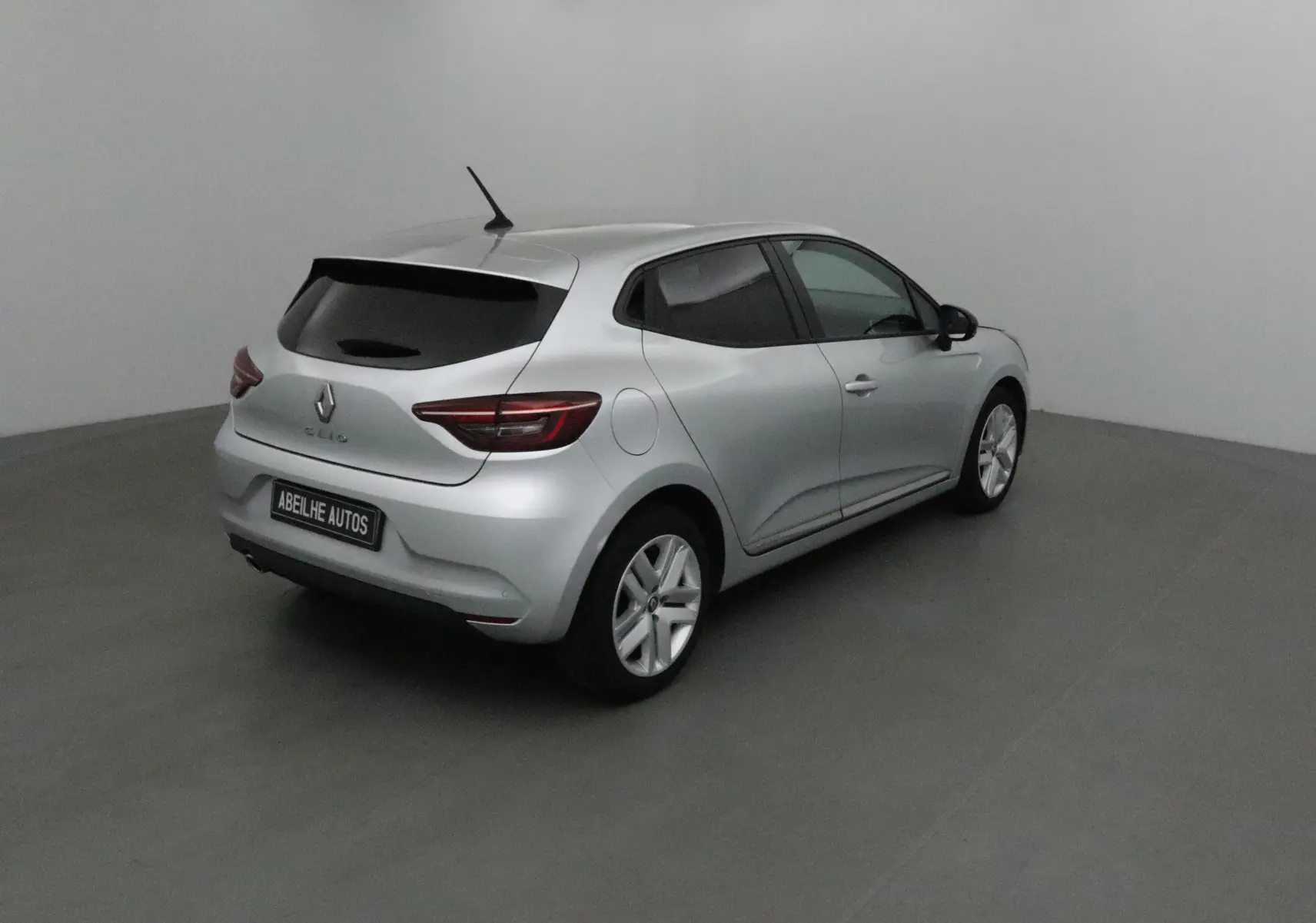 Renault Clio V gris platine vue 3/4 arrière droit dans un studio, avec vitres teintées et jantes alliage.