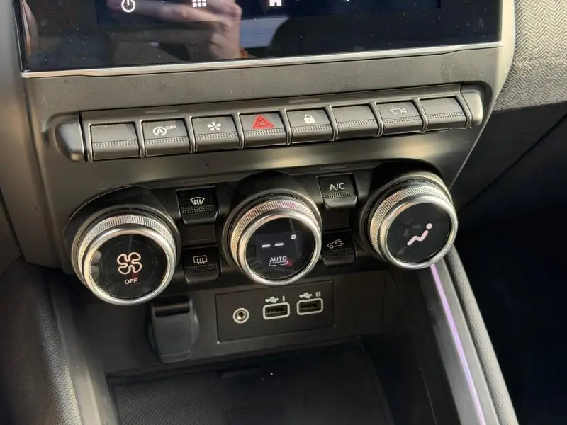 Vue rapprochée des commandes de climatisation et des ports USB intérieurs de la Renault Clio Rouge Flamme 2025.