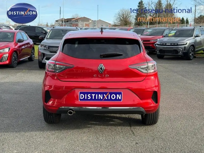 Vue arrière d'une Renault Clio rouge flamme 2025 avec feux arrière LED et sortie d'échappement chromée visible.