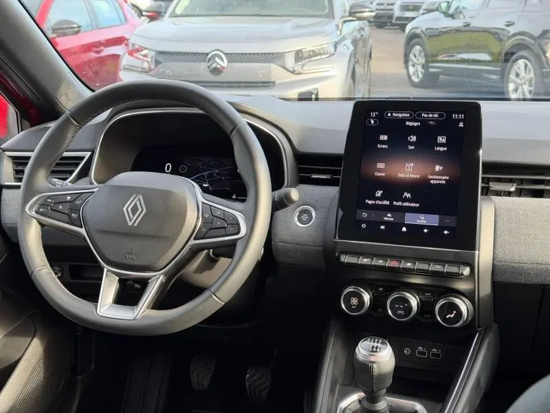 Vue intérieure de face du tableau de bord de la Renault Clio rouge avec écran tactile vertical et volant multifonction.