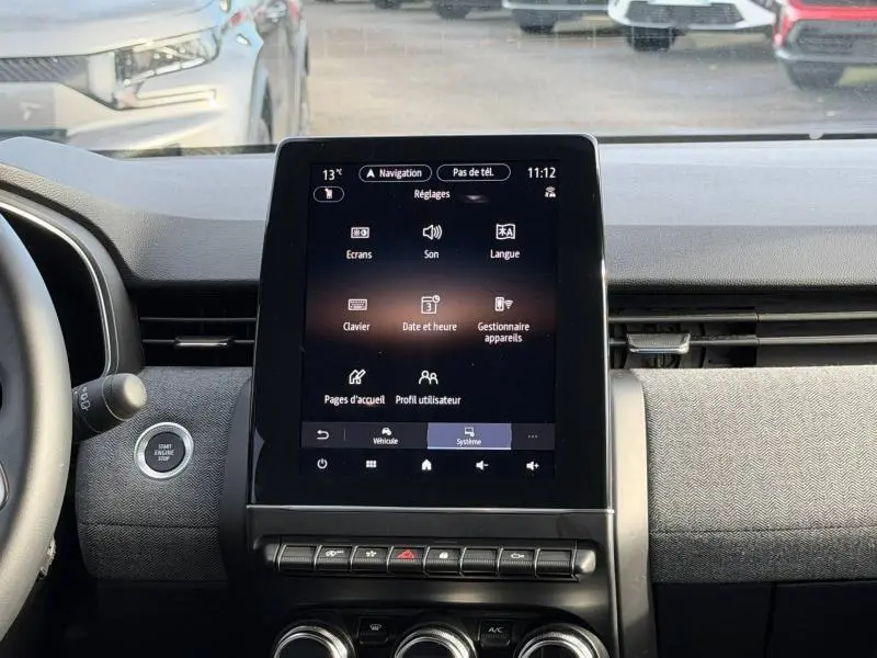 Vue intérieure centrée sur l’écran tactile multifonction du tableau de bord de la Renault Clio rouge flamme 2025.