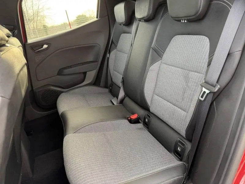 Vue latérale droite de la banquette arrière grise et noire de la Renault Clio Rouge Flamme 2025 avec ceintures de sécurité visibles.