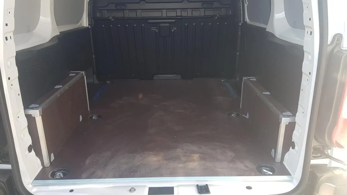 Vue intérieure arrière du Citroën Berlingo blanc 2025, montrant l'espace de chargement vide et les parois latérales.