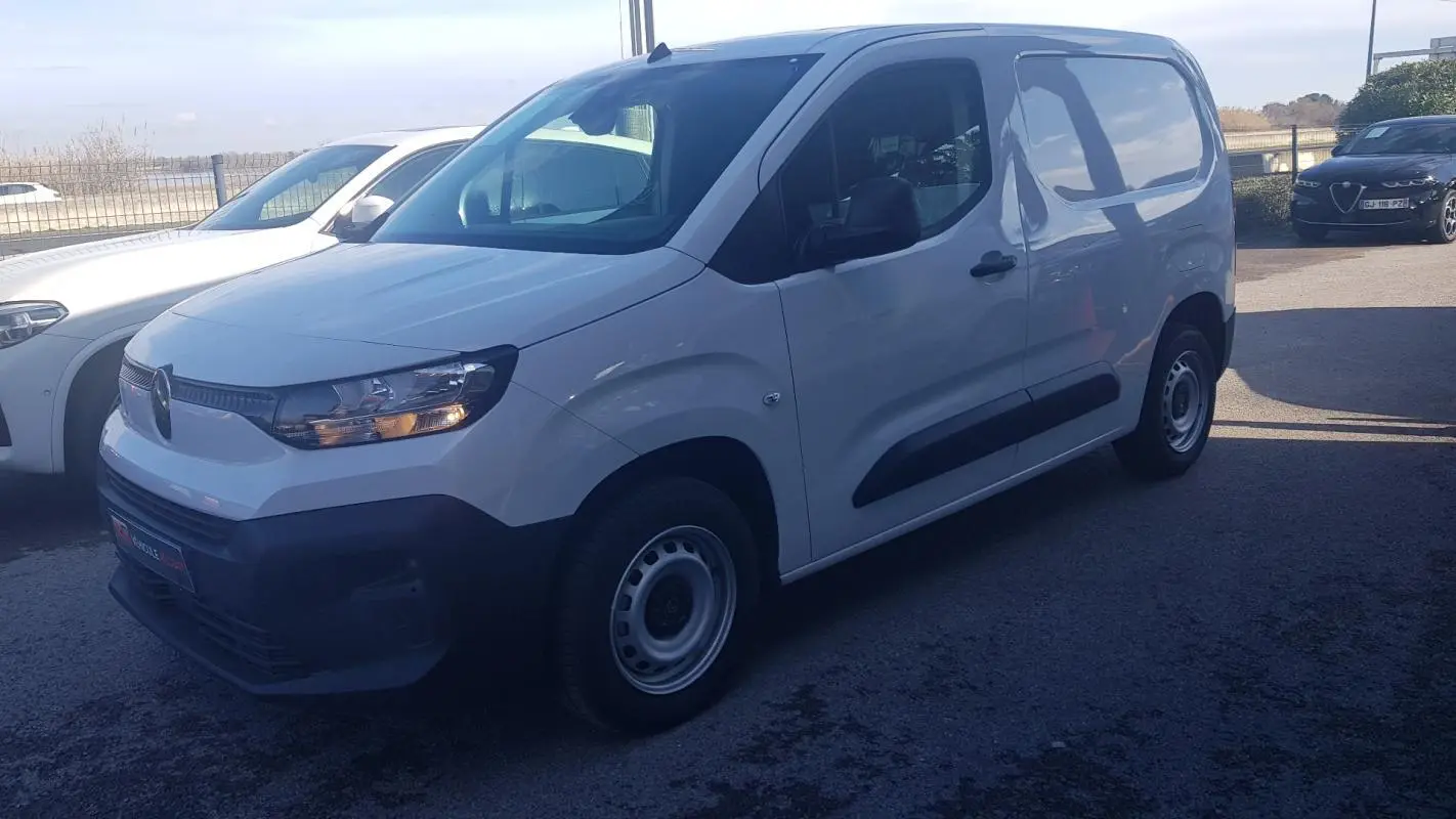 Vue 3/4 avant gauche d’un Citroën Berlingo blanc 2025 avec porte latérale et jantes acier 15 pouces.