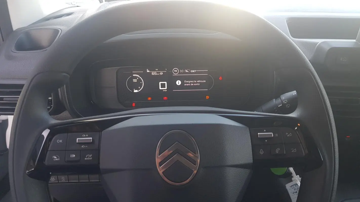 Vue rapprochée du volant multifonctions noir et du tableau de bord numérique du Citroën Berlingo blanc 2025.