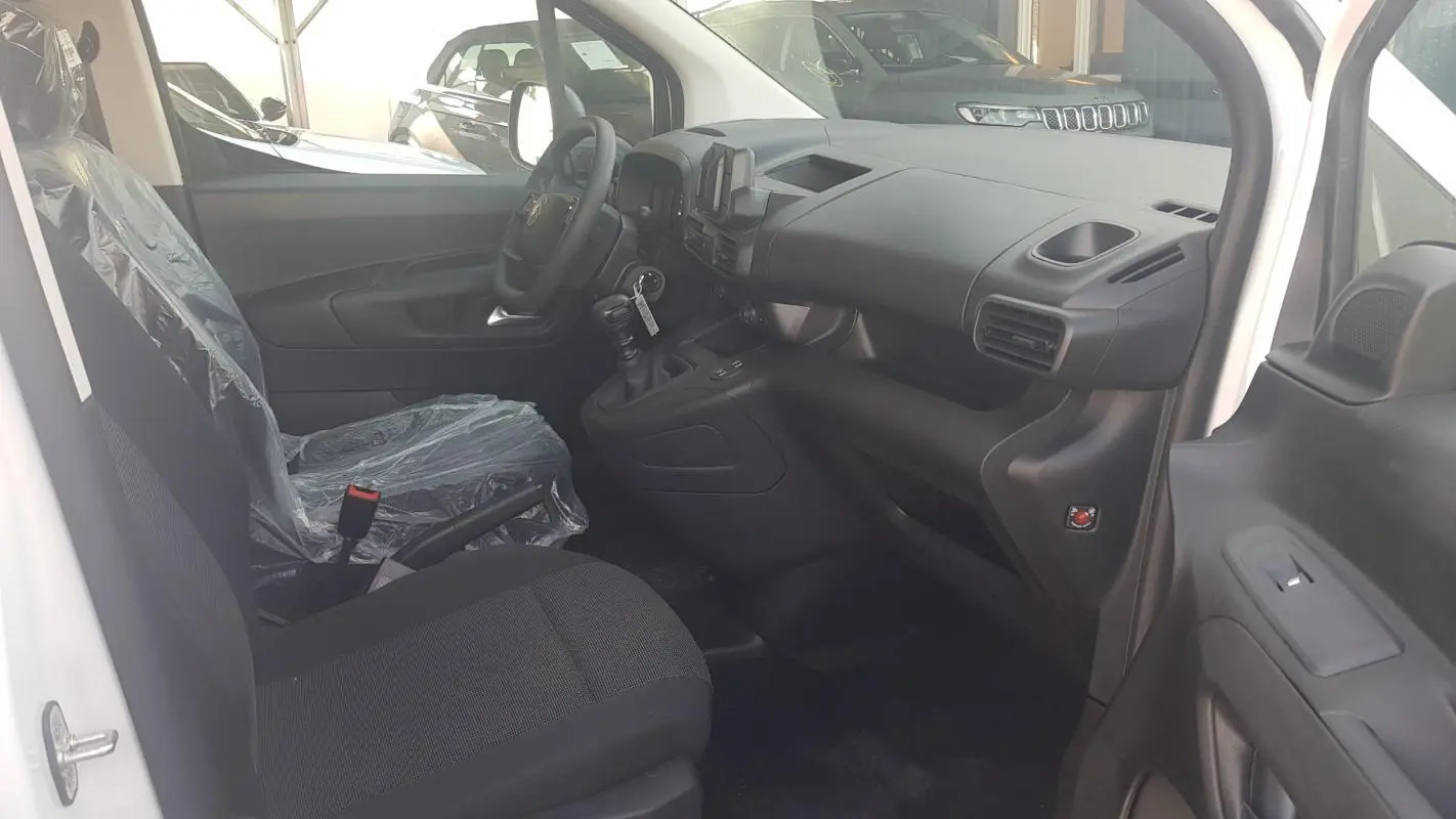 Vue intérieure côté conducteur du Citroën Berlingo blanc 2025, montrant le volant multifonctions et la boîte manuelle.