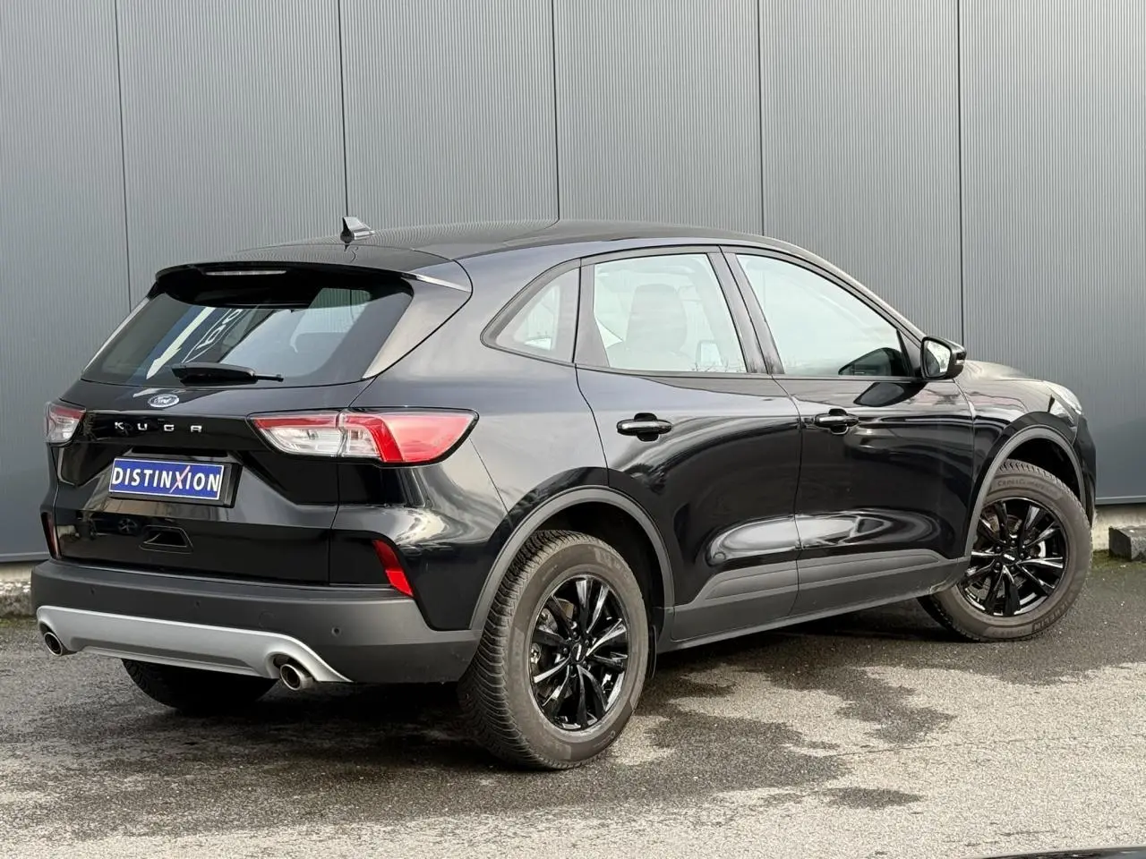 Vue 3/4 arrière droite d'un Ford Kuga 2024 noir Obsidien avec jantes alliage noires et double sortie d'échappement.
