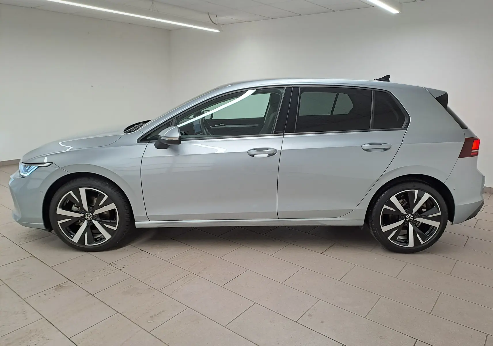 Vue de profil côté gauche d'une Volkswagen Golf 1.5 eTSI 116 BVM6 VW Edition argent Dolomite avec jantes alliage 18 pouces.