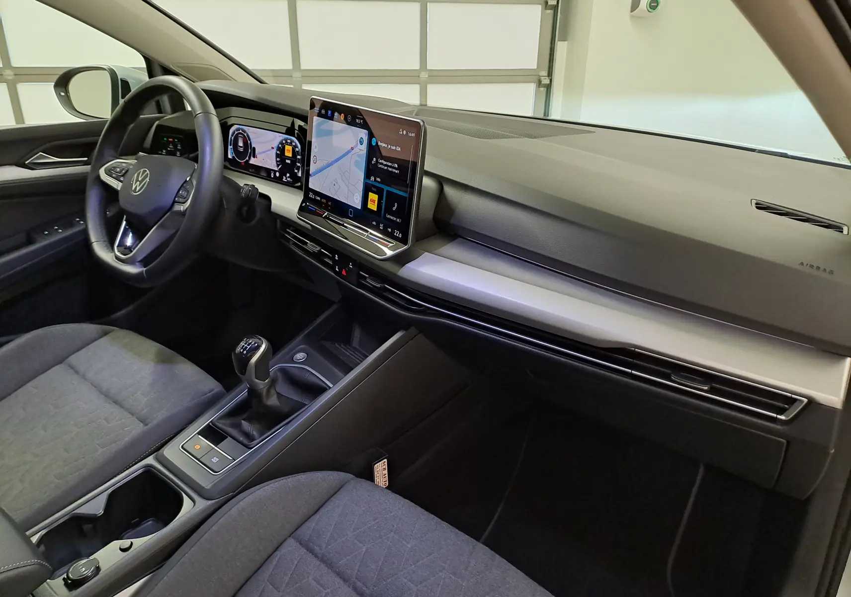 Vue intérieure côté conducteur de la Volkswagen Golf 1.5 eTSI 2025 avec tableau de bord numérique et écran tactile central.
