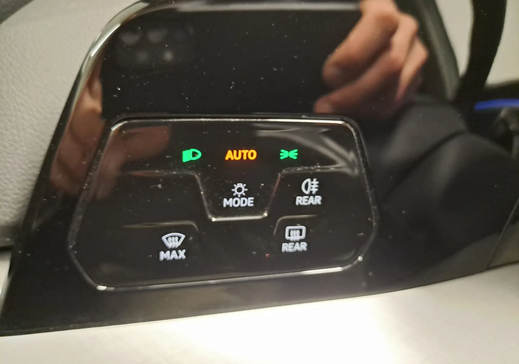 Panneau de commandes d’éclairage et désembuage intérieur noir brillant avec voyants verts et orange dans un Volkswagen Golf 2025.
