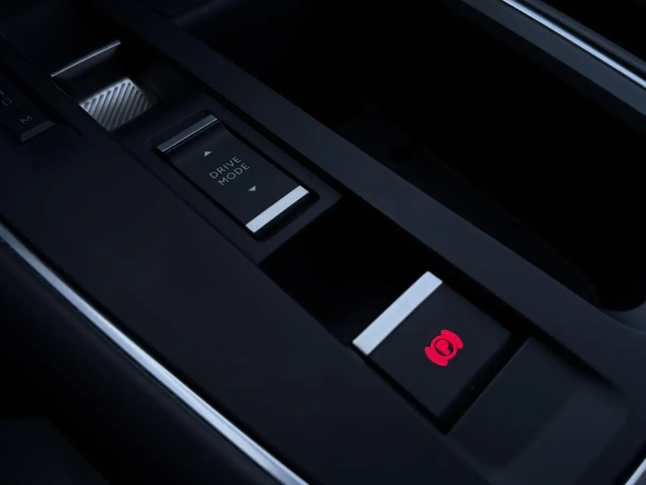 Gros plan sur la console centrale noire du Citroën C5 Aircross Hybrid avec bouton frein électrique illuminé en rouge.