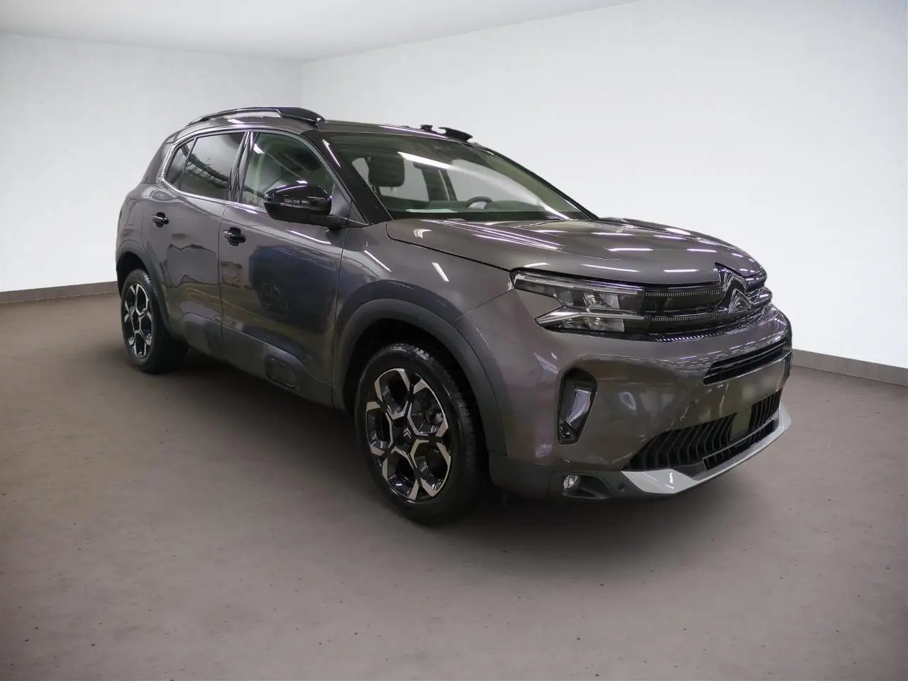 Citroën C5 Aircross Hybrid gris Platinium en 3/4 avant droit, avec jantes alliage bi-ton et barres de toit noires.