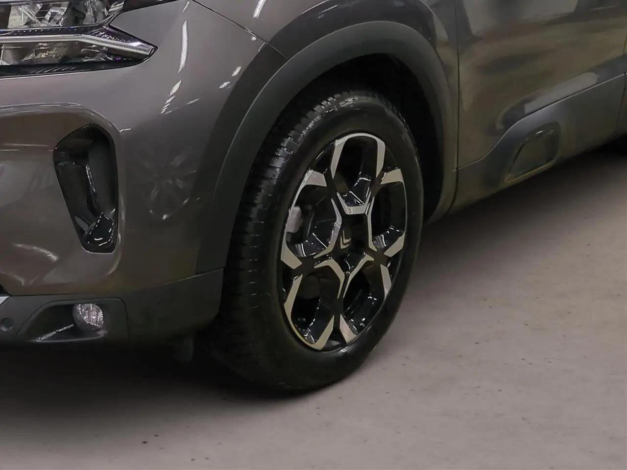 Gros plan sur la roue avant droite et partie du pare-chocs gris Platinium du Citroën C5 Aircross Hybrid 2025.