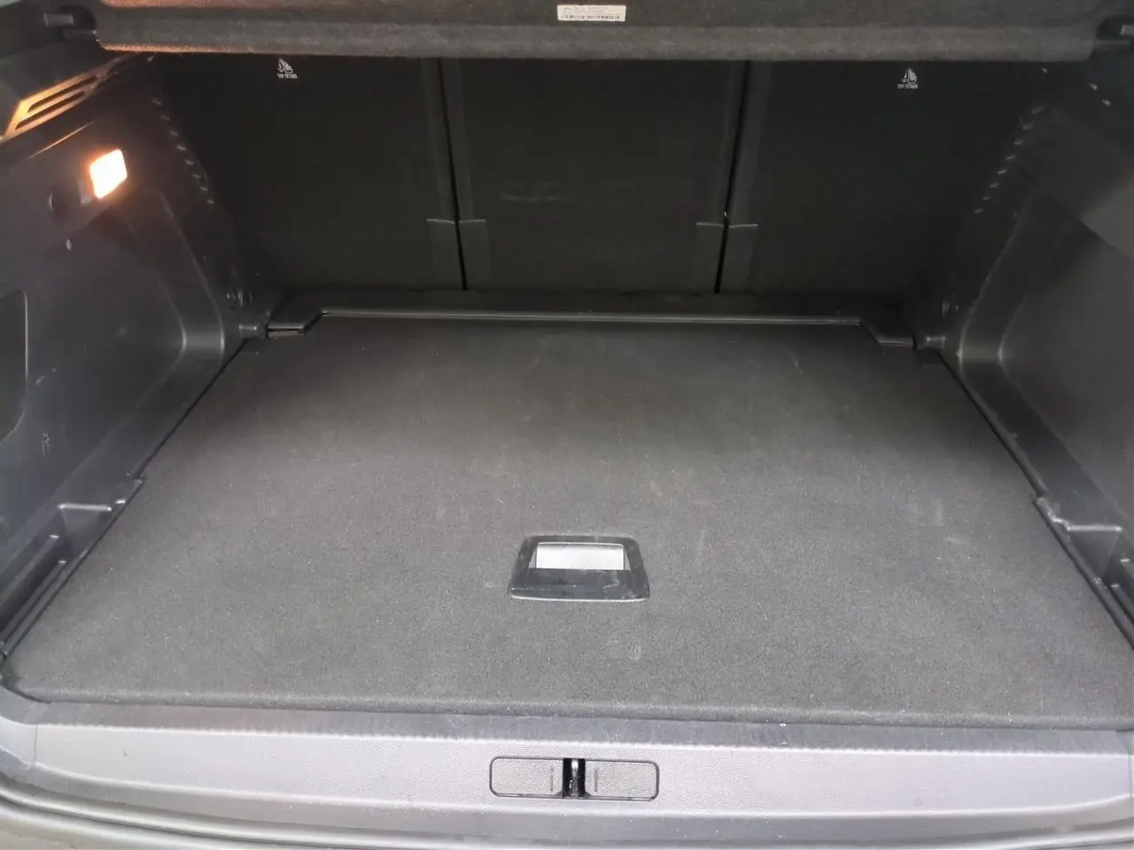 Coffre ouvert vu de face d’un Citroën C5 Aircross Hybrid gris Platinium avec hayon électrique et éclairage intérieur.